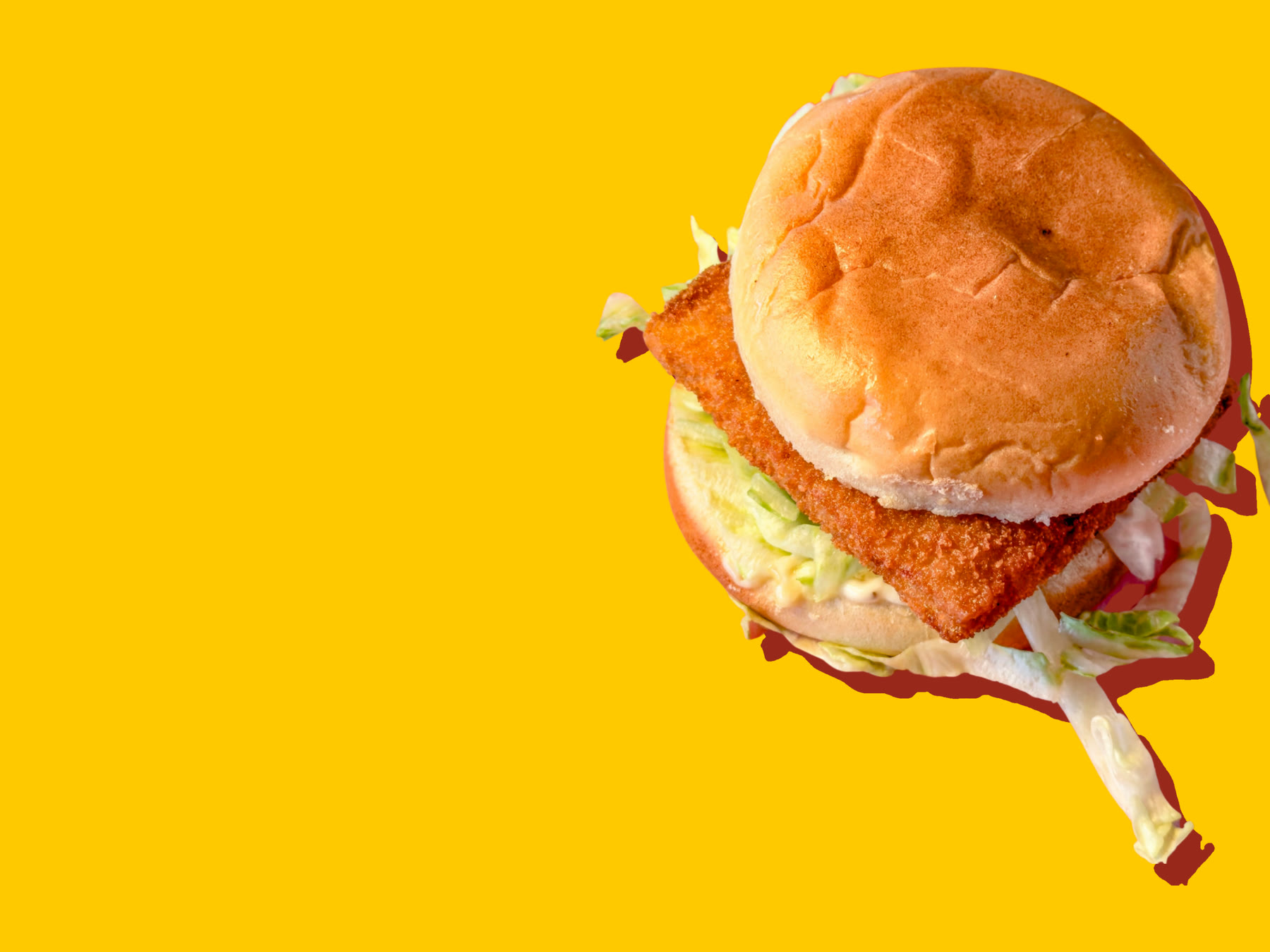 A fish sandwich: fried cod with tartar sauce and shredded lettuce on a soft bun